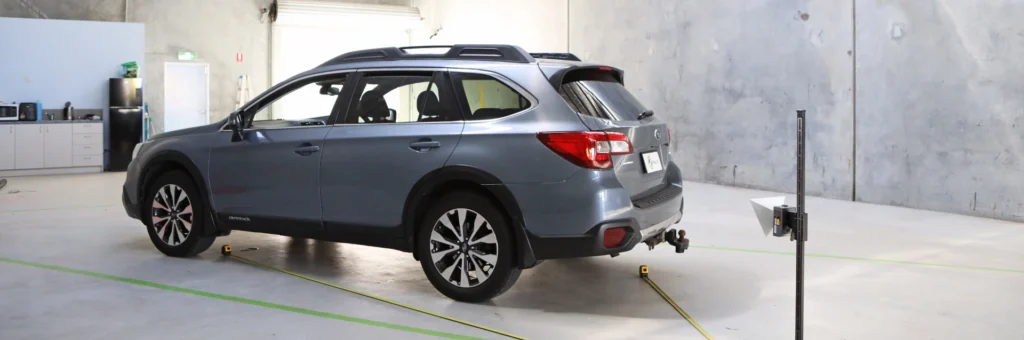 Blue Subaru Outback aligned in calibration bay with ADAS target setup