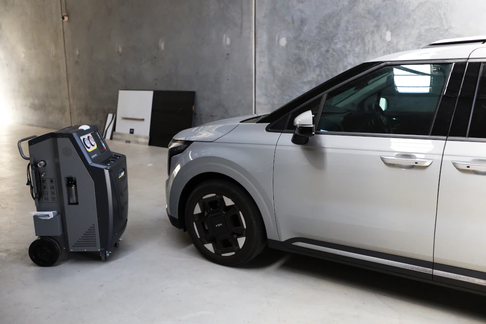Car positioned next to a 1234YF air conditioning regas machine for refrigerant servicing