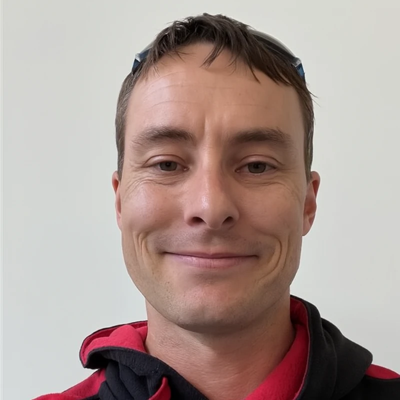 Male technician wearing red and black hoodie, smiling at camera